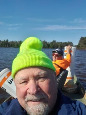 older man taking a selfie on a boat on the lake with a man behind him